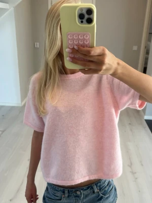 Stickad  topp - Supermjuk och fluffig ljusrosa stickad topp med korta ärmar och rund hals. Toppen har en loose passform och är perfekt för en chill och avslappnad stil. Materialet känns mysigt och färgen är riktigt söt pastellrosa.
