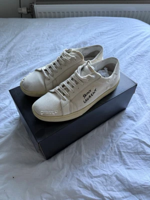 Saint Laurent SL/06  - Saint Laurent (YSL) SL/06 Signature Sneakers – Beige  Säljer ett par Saint Laurent SL/06 Signature sneakers i beige. Skorna är sparsamt använda och i mycket fint skick.  Detaljer:  * Modell: Saint Laurent SL/06 Signature * Färg: Beige  * Skick: Väldigt bra skick * Sparsamt använda * Originalkartong medföljer * Originalsnören medföljer * Nypris: ca 7 900 kr