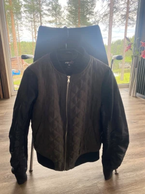 FB Sister quiltad bomberjacka - stl M - Snygg svart bomberjacka från FB Sister i storlek M. Jackan har quiltat mönster på framsidan, ribbade muddar vid ärmslut och nederkant samt dragkedja framtill. Perfekt för dig som vill ha en stilren och trendig look.