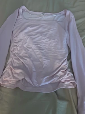 Ljusrosa långärmad topp - Snygg ljusrosa långärmad topp med fyrkantig ringning. Tillverkad i mjukt och stretchigt material som sitter skönt på kroppen. Perfekt att styla med jeans eller kjol för en clean look.