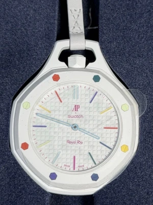 Swatch x AP Royal Pop Huit Blanc klocka - Unik vit klocka från Swatch x Audemars Piguet Royal Pop-kollektionen. Klockan har en oktagonal form, färgglada index och detaljer, samt vit rem. Urtavlan har ett rutigt mönster och boetten är i biokeramik. Perfekt för dig som gillar statement-accessoarer.