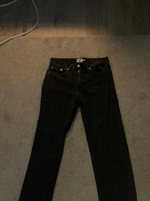 Svarta raka jeans från lager 157 - Säljer ett par svarta jeans från lager 157 med rak passform och klassisk femficksdesign. Jeansen har knappgylf och är tillverkade i ett slitstarkt denimtyg. Perfekta för en clean och tidlös look. Jeansen är seattle och lite större inte som slim fit.