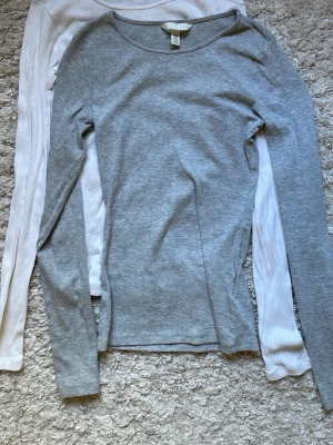 Grå och vit ribbad långärmad topp H&M - Två långärmade toppar från H&M i storlek XS, en i ljusgrått och en i vitt. Den vita är mer använd än den grå, den grå är typ som ny.