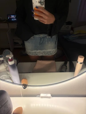 Ljus jeanskjol med spetskant - Kort ljusblå jeanskjol med vit spetsdetalj längst ner. Kjolen har klassiska fickor fram och en snygg tvättad look. Perfekt för dig som vill ha en söt och trendig stil.
