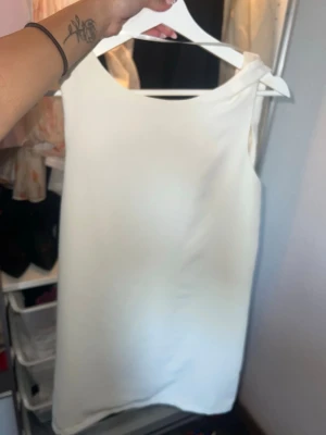 Vit ärmlös klänning från Vila - Stilren vit klänning från Vila i storlek XS. Klänningen är ärmlös med enkel, rak passform och tillverkad i ett lätt, slätt material som ger en elegant look. Perfekt för sommarens alla tillfällen.