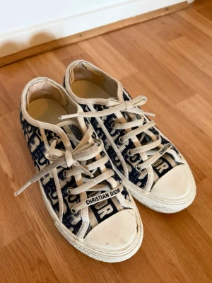 Christian Dior Oblique sneakers - Snygga låga sneakers från Christian Dior med klassiskt blått och vitt oblique-mönster. Skorna har vita snören, gummisula och detaljer med logotyp på tån och sidan. 