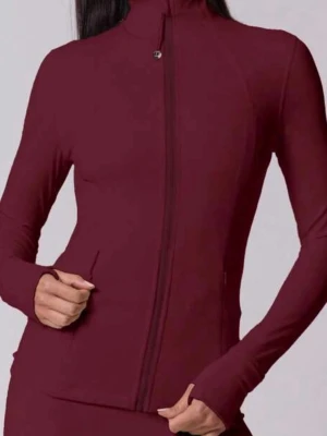 Vinröd träningsjacka med dragkedja - Vinröd träningsjacka med hel dragkedja framtill och hög krage. Jackan har långa ärmar och är figursydd för en sportig look. Perfekt för gymmet eller löprundan. Materialet ser ut att vara stretchigt och bekvämt.