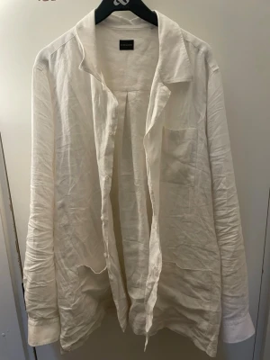Vit linneskjorta från Rose & Born - Snygg vit skjorta i linne från Rose & Born. Skjortan har lång ärm, klassisk krage, bröstficka och knäppning framtill. Perfekt för en avslappnad och stilren look. Behöver endast strykas