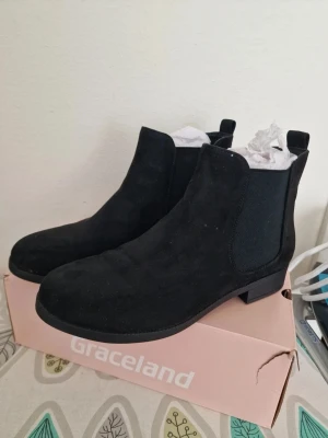 Svarta Chelsea boots från Dinsko - Stilrena svarta Chelsea boots från Dinsko  i mockaimitation med klassiska resårpaneler på sidorna och låg klack. Perfekta för dig som vill ha en tidlös och enkel look till hösten eller vintern. Storlek 39. Perfekt skick