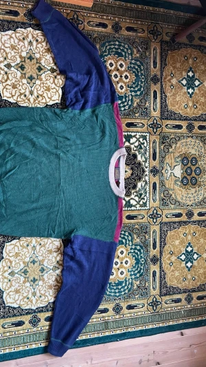 Flerfärgad stickad tröja från Eddie Bauer - Säljer en unik stickad tröja från Eddie Bauer i storlek L. Tröjan har grön kropp, blå ärmar, vinröda axelpartier och beige ribbad krage. Tillverkad i 100% bomull, perfekt för dig som gillar retrovibbar och färgkombinationer.