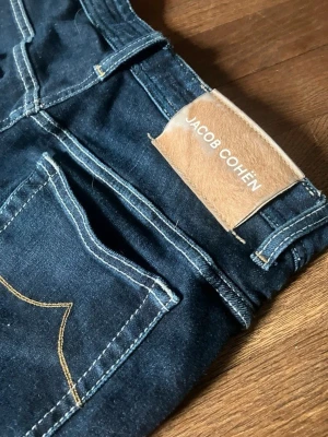 Jacob Cohën - Mörkblå Jeans - Lyxiga Jacob Cohën Leonard jeans i storlek 46/W30 – ett av världens mest eftertraktade denimmärken! Jeansen är i mycket bra skick och håller den höga kvalitet som märket är känt för. Perfekt för dig som vill uppgradera garderoben med ett premium-plagg till ett bråkdel av butikspriset. Passa på – sådana här fynd försvinner snabbt!
