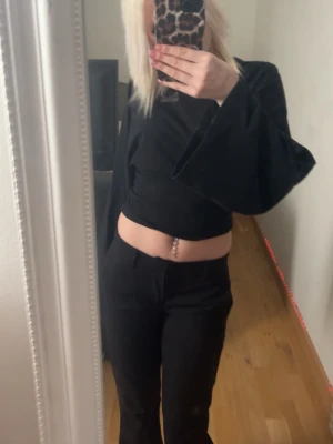 Svarta kostymbyxor med rak passform - Säljer ett par svarta kostymbyxor med rak passform och normal midja. Byxorna har klassisk look och är tillverkade i ett slätt tyg som ger en stilren känsla. Perfekta att matcha med crop top eller skjorta för en trendig outfit.