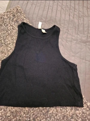 Linnetopp H&M Divided S - Svart ribbad linnetopp H&M Divided  En svart, croppad linnetopp från H&M Divided. Toppen är ribbad och ärmlös med rund halsringning. Perfekt för att styla med jeans eller kjol för en clean look.  Kan även hämtas I Partille  E1