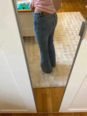 Bootcut jeans i ljusblå denim - Säljer ett par ljusblå bootcut jeans med hög midja och framfickor. Jeansen har en klassisk femficksdesign och är tillverkade i mjuk denim. Perfekta för en avslappnad och trendig look.