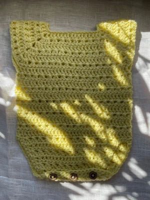 Handvirkad babyromper gul 50–56 - Handvirkad babyromper i mjuk gul nyans, en enkel och tidlös modell som passar både till vardag och sommar. Knäpps med knappar nedtill för smidig på- och avklädning. Varje plagg är unikt och gjort för hand. Storlek ca 50/56, nyfödd till cirka 2 månader. Mått: längd ca 31 cm, bredd under armarna ca 23 cm, bredd halshål ca 10 cm, ärmhål ca 9 cm. Rekommenderas att jämföra med måtten. Material: akrylgarn som är mjukt, lätt och praktiskt i skötsel. Perfekt som present eller som ett fint första plagg. 