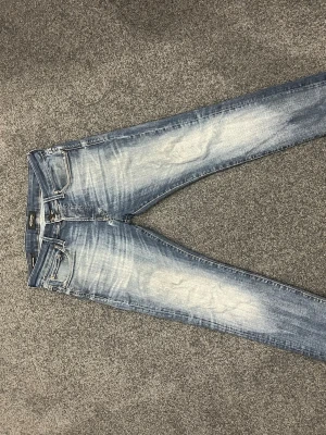 Slim fit ljusblå jeans med slitningar - Säljer ett par slim fit jeans i ljusblå denim med snygga slitningar och tvättade detaljer. Klassisk femficksmodell med dragkedja och knapp. Perfekta för en avslappnad och trendig look.