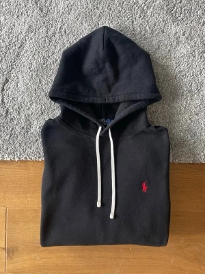 Svart hoodie från Polo Ralph Lauren - Svart Ralph Lauren hoodie i storlek M säljes. I mycket bra skick och utan defekter. Stilren och bekväm hoodie som passar till allt.  ✅ Storlek M ✅ Mycket bra skick ✅ Inga defekter ✅ Snabb frakt  Hör gärna av er vid frågor eller om ni vill ha fler bilder!