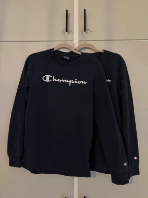 Champion sweatshirt x2 - Säljer två sweatshirt från Champion med klassisk logga i vitt över bröstet och liten logga på ärmen. Tröjorna har rund halsringning och ribbade muddar vid ärmslut och nederkant. De säljs tillsammans och priset inkluderar båda två. Är från barnavdelningen så XL motsvarar 13/14 år.