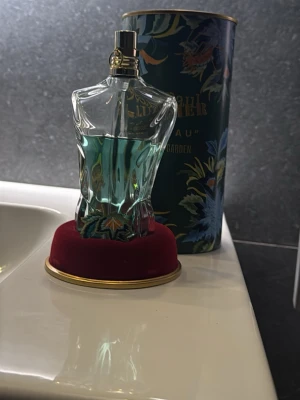 Jean Paul Gaultier Le Beau Paradise Garden - Unik parfym från Jean Paul Gaultier, Le Beau Paradise Garden, i en cool flaska formad som en manlig torso med blågrön vätska. Kommer i en dekorativ tub med blommigt mönster och gulddetaljer. Perfekt för dig som gillar exklusiva och iögonfallande dofter.