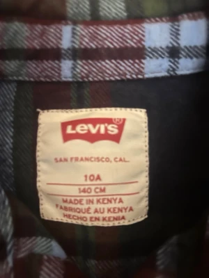 Rutig skjorta från Levi's i blått och rött - Klassisk rutig skjorta från Levi's i mörkblått, rött och vitt. Skjortan har lång ärm, bröstficka och knappar framtill. Perfekt för en avslappnad och cool stil. Tillverkad i mjuk bomull för skön känsla.