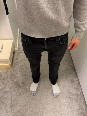 Nudie jeans - Säljer ett par svarta skinny jeans från Nudie Jeans. Modellen har smal passform, klassisk femficksdesign och svarta sömmar. Jeansen är i stretchigt material för extra komfort och har en snygg tvättad look.