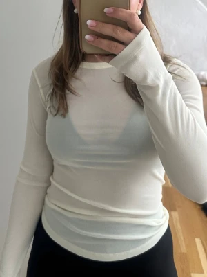 Vit långärmad mesh-top - Snygg vit långärmad mesh-top med tight passform. Tunt och lätt material som ger en trendig och stilren look. Perfekt att styla lager på lager eller bära som den är för en clean vibe.