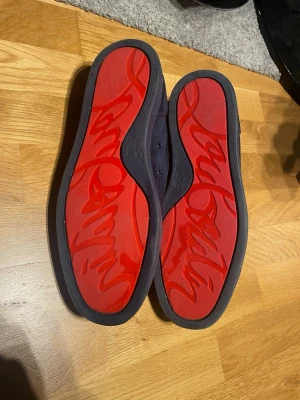 Mörkblå Christian Louboutin sneakers - Snygga mörkblå sneakers från Christian Louboutin med klassisk röd sula. Svårt att sälja sånna här skor men försöker. Ställ frågor om ni undrar något 