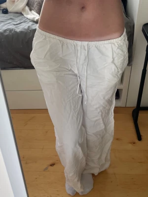 Vita linnebyxor - Säljer ett par vita linnebyxor med avslappnad passform och resår i midjan med dragsko. Byxorna har raka ben och två stora bakfickor. Perfekta för varma dagar.
