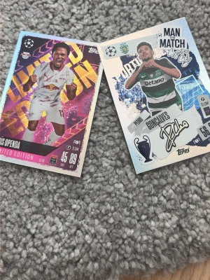 Fotbollssamlarbilder från Topps - Två fotbollssamlarbilder från Topps, en med färgstark bakgrund och text 'Limited Edition', den andra med silverglans och 'Man of the Match'-tema. Båda har spelarbilder, klubbemblem och detaljer som statistik och autograftryck.