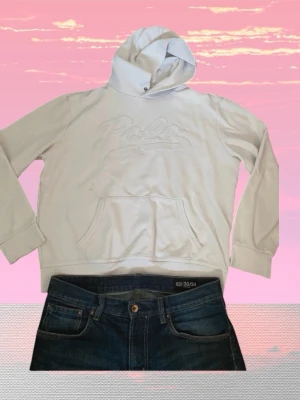Vit hoodie från Polo Ralph Lauren - Snygg vit hoodie från Polo Ralph Lauren med broderad logga på bröstet. Klassisk modell med huva och känguruficka framtill. Tillverkad i mjukt bomullsmaterial som känns skönt mot huden. Perfekt för en avslappnad och trendig stil.