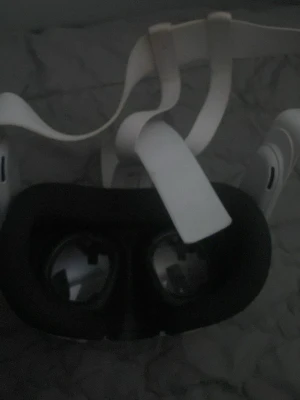 Oculus Quest 2 VR-headset vitt - Säljer ett Oculus Quest 2 VR-headset i vitt med justerbart huvudband och bekväm svart ansiktsdyna. Headsetet har tre kameror på framsidan och stora linser för en uppslukande VR-upplevelse. Perfekt för gaming och VR-upplevelser.