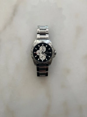 Festina herrklocka i silver - Stilren herrklocka från Festina med silverfärgad länk i metall och svart urtavla. Klockan har tre mindre vita urtavlor, tydliga index och robust boett. Perfekt accessoar för dig som gillar klassisk och sportig stil.