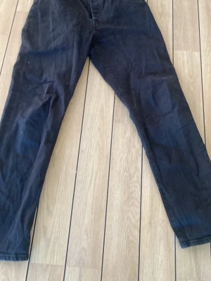 Svarta raka jeans från Levi's - Svarta jeans från Levi's med klassisk rak passform och femficksdesign. Jeansen har en läderpatch bak i midjan och är tillverkade i ett slitstarkt bomullstyg. Perfekta för en avslappnad och stilren look.
