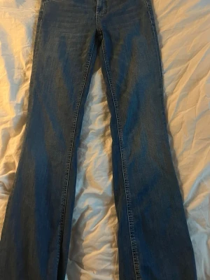 Blå bootcut jeans från Zara - Snygga blå bootcut jeans från Zara med klassisk femficksdesign och normalhög midja. Jeansen har en lätt tvättad look och är tillverkade i denim med lite stretch för extra komfort. Perfekta för en avslappnad och trendig stil.