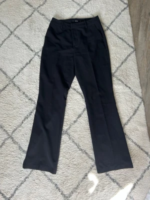 Svarta kostymbyxor från BikBok - Stilrena svarta kostymbyxor från BikBok med rak passform och diskret utsvängda ben. Vanlig längd på benen. Är modellen Vera. 