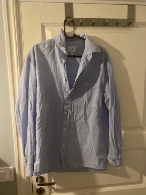Ljusblå skjorta från H&M Relaxed Fit - Snygg ljusblå skjorta från H&M i relaxed fit. Skjortan har klassisk krage, knäppning framtill och långa ärmar. Perfekt för en chill och stilren look. Tillverkad i bomull för en skön känsla hela dagen. 