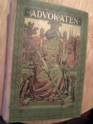 Advokaten - Juridisk rådgivare - Säljer boken 'Advokaten', en juridisk rådgivare för var man. Omslaget är grönt med detaljerad illustration i brunt och guld, samt dekorativa mönster runt kanterna. Titeln och texten på ryggen är i guldtext. Perfekt för dig som gillar klassiska böcker med unika omslag.