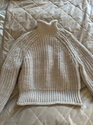 Beige stickad polotröja - Säljer en chunky beige stickad polotröja med grov ribbstickning. Tröjan har lång ärm, hög polokrage och breda muddar vid ärmslut och nederkant. Perfekt för kyliga dagar och superenkel att styla till jeans eller kjol. Storlek XS!🩷