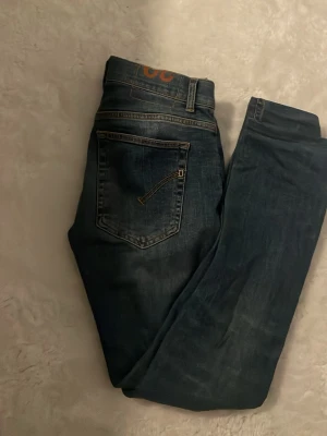 Blå jeans från Dondup  - Säljer ett par klassiska blå jeans från Dondup med femficksmodell och snygga slitningar. Jeansen har normal midja och raka ben, tillverkade i mjukt denimtyg. Perfekta för en avslappnad och trendig look.