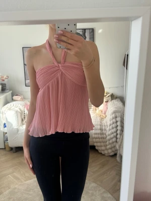 Rosa halterneck topp - Söt rosa halterneck topp med twistad detalj framtill. Toppen är ärmlös och har en flowy passform med tunna axelband som knyts i nacken. Perfekt för varma dagar och snygg att styla med jeans eller kjol💞köpt här på Plick