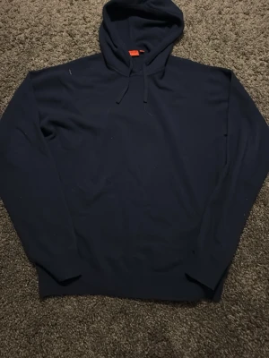 Stickad Mörkblå hoodie från RYVLS - Snygg mörkblå hoodie från RYVLS med klassisk huva och dragsko. Perfekt för en chill och avslappnad stil. Tillverkad i mjukt material som känns skönt mot huden. Passar dig som gillar enkel och stilren design.