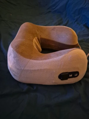 Beige massage-nackkudde elektronik - Elektronisk massage-nackkudde i beige plyschmaterial med U-formad design. Kudden har inbyggda knappar för styrning av massagefunktion och är perfekt för resor eller avkoppling hemma. Smidig att ta med och ger extra komfort för nacken.