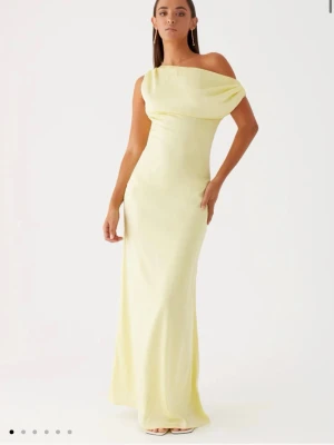 Ljusgul långklänning med oneshoulder - Elegant ljusgul långklänning med oneshoulder-design och mjukt fall. Klänningen har en asymmetrisk axel och smickrande passform som framhäver siluetten. Oanvänd och super fin!! 