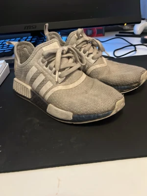 Beige Adidas NMD_R1 sneakers - Säljer ett par vita Adidas NMD_R1 sneakers med stickad ovandel och de klassiska tre ränderna på sidan. Om du funderar på något hör av dig 🫡
