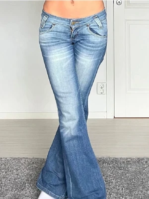 Blå bootcut jeans från Lee - Snygga blå bootcut jeans från Lee med låg midja och klassiska fickor både fram och bak. Jeansen har ljusa slitningar framtill och Lee-logga på bakfickan. midjemått: 36 cm rakt över, innerbenslängd: 83 cm💞