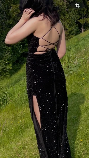 Balklänning - Säljer min fina balklänning. Den är svart med paljetter som glittrar. Två slits på båda benen och snörad öppen rygg. Väldigt stretchig och går till fötterna på mig som är 160cm. Köpt på plick så har använts minst 2 gånger.