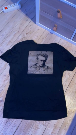 Limitato T-shirt - Cool svart t-shirt med korta ärmar och ett stort grafiskt tryck på ryggen i beige och svart. Trycket föreställer en siluett med små prickar. Perfekt för dig som gillar unika motiv och streetstyle.