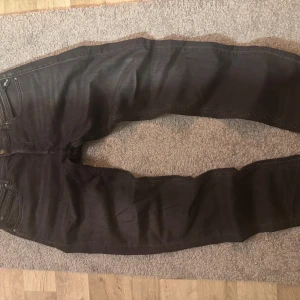 Svarta slim fit jeans replay - Säljer ett par svarta slim fit jeans med klassisk femficksdesign och dragkedja. Jeansen har smal passform och raka ben, perfekta till en avslappnad stil. Materialet är troligtvis bomull med lite stretch för extra komfort.