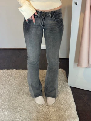 Grå bootcut jeans med slitningar - Snygga grå bootcut jeans med lätt slitna detaljer och klassisk femficksmodell. Omsydda i benen så att de är bootcut. Stretchigt material så passar även en storlek större