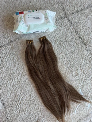 Långa bruna löshår extensions 100g - Säljer två paket med långa, raka löshår extensions i en naturlig brun nyans. Perfekta för dig som vill ha extra volym och längd till håret. Fästes enkelt med clips. Materialet är syntetiskt och känns mjukt och följsamt.